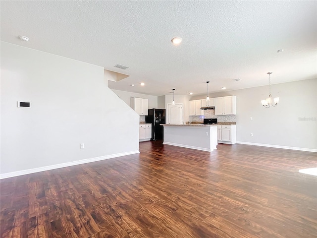 unfurnished living room featuring dark hardwood / wood-style flooring, a textured ceiling, and a chandelier