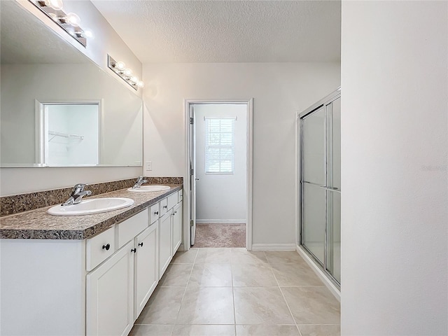 bathroom with tile patterned floors, vanity, a shower with shower door, and a textured ceiling