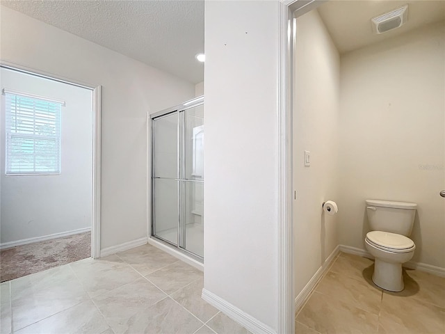 bathroom featuring a shower with door, tile patterned flooring, a textured ceiling, and toilet