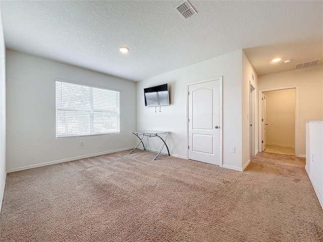 carpeted empty room featuring a textured ceiling