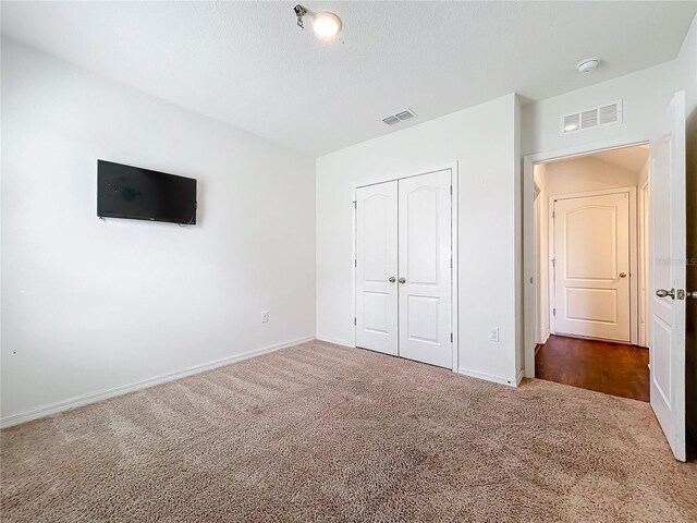 unfurnished bedroom with carpet floors, a textured ceiling, and a closet