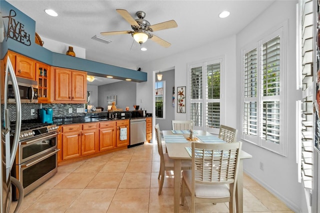 kitchen with backsplash, ceiling fan, light tile patterned floors, and stainless steel appliances