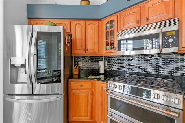 kitchen featuring dark stone counters, backsplash, and stainless steel appliances