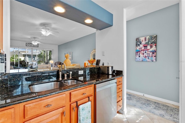 kitchen featuring dishwasher, light tile patterned floors, sink, and dark stone counters