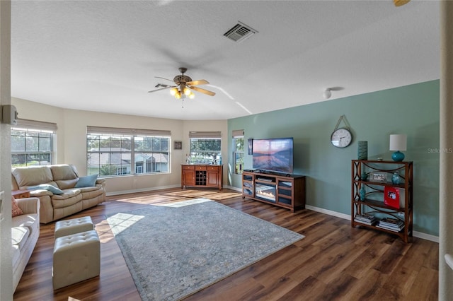 living room with ceiling fan, dark hardwood / wood-style flooring, and a textured ceiling