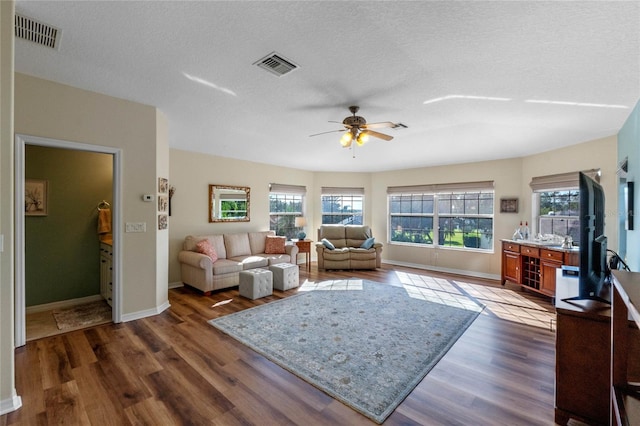 living room featuring a textured ceiling, dark hardwood / wood-style floors, and ceiling fan