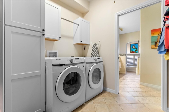 washroom with cabinets, light tile patterned floors, and washing machine and clothes dryer