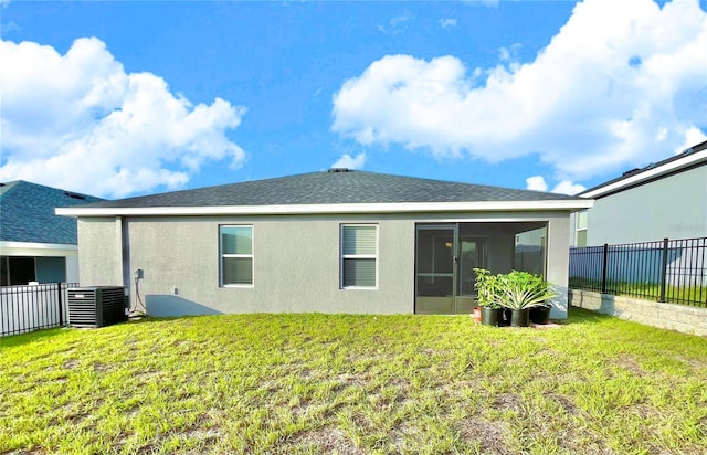 back of property with central AC unit, a sunroom, and a yard