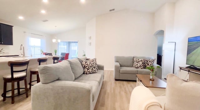 living room with light hardwood / wood-style floors, high vaulted ceiling, and a notable chandelier