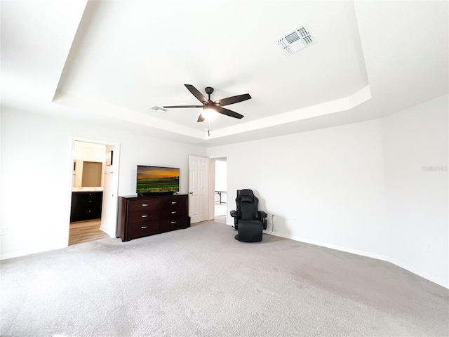 unfurnished bedroom featuring light carpet, a raised ceiling, and ceiling fan