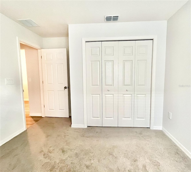 unfurnished bedroom with light carpet and a closet