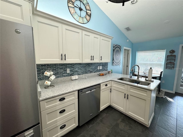 kitchen with kitchen peninsula, appliances with stainless steel finishes, light stone counters, sink, and lofted ceiling