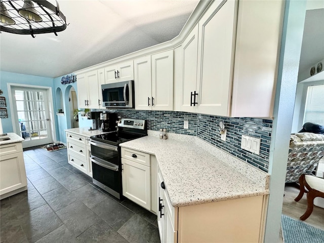 kitchen with white cabinets, appliances with stainless steel finishes, and light stone counters