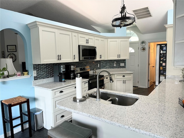 kitchen featuring a kitchen bar, hanging light fixtures, appliances with stainless steel finishes, light stone counters, and kitchen peninsula