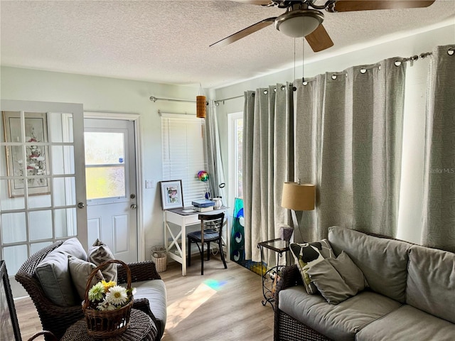 living room with a textured ceiling, light hardwood / wood-style floors, ceiling fan, and a healthy amount of sunlight