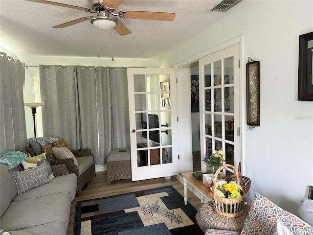 living room featuring french doors, a textured ceiling, ceiling fan, and dark wood-type flooring