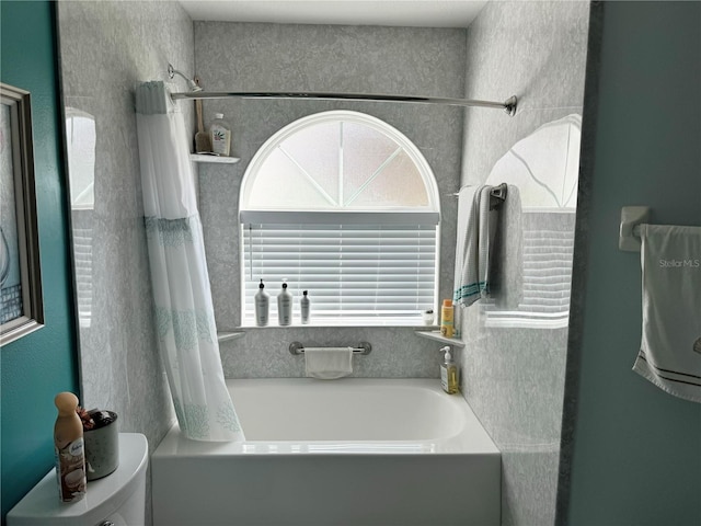 bathroom with shower / bath combination with curtain and toilet