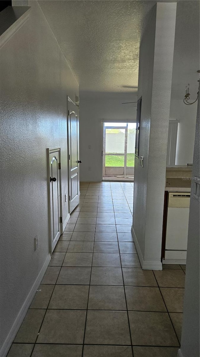 corridor with a textured ceiling and tile patterned floors