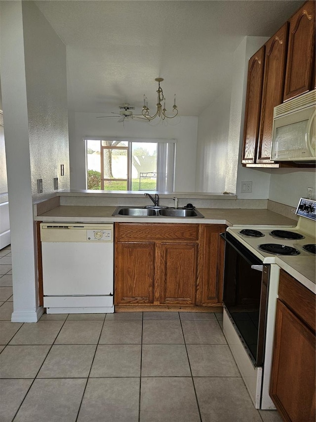 652 Chelsea Dr, Davenport, FL 33897 - kitchen with white appliances, a sink, light tile patterned floors, light countertops, and brown cabinetry