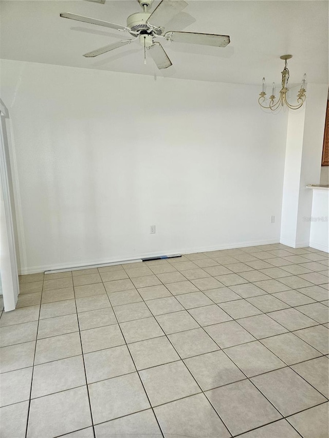 tiled empty room featuring ceiling fan with notable chandelier