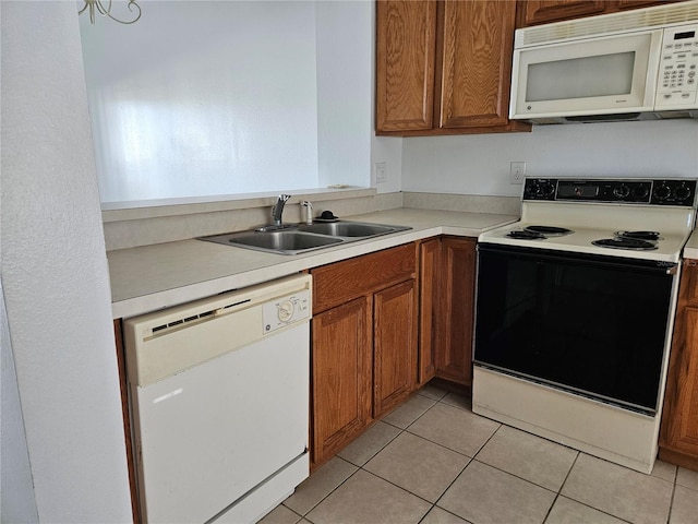 kitchen with light tile patterned floors, white appliances, and sink