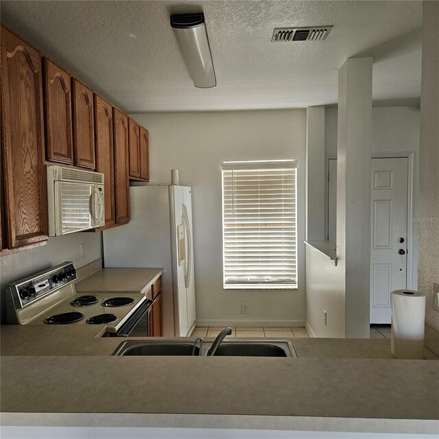 652 Chelsea Dr, Davenport, FL 33897 - kitchen with white appliances, light tile patterned floors, a sink, brown cabinets, and a textured ceiling