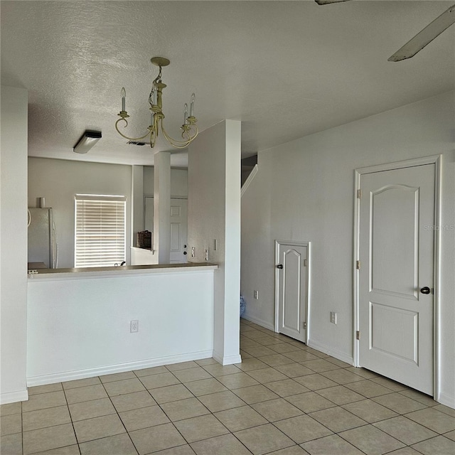 652 Chelsea Dr, Davenport, FL 33897 - tiled empty room featuring a chandelier, a textured ceiling, and baseboards