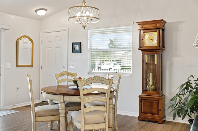 dining space featuring dark hardwood / wood-style floors, vaulted ceiling, and a notable chandelier