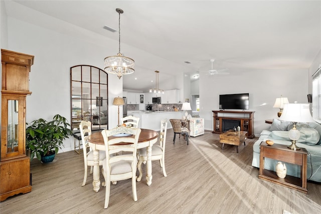 dining room with light hardwood / wood-style flooring and ceiling fan with notable chandelier