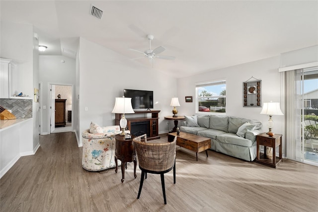 living room featuring ceiling fan, lofted ceiling, and light hardwood / wood-style flooring