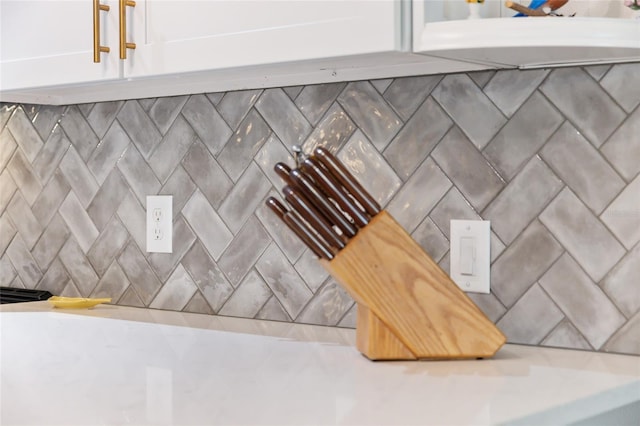 interior details featuring tasteful backsplash and white cabinetry