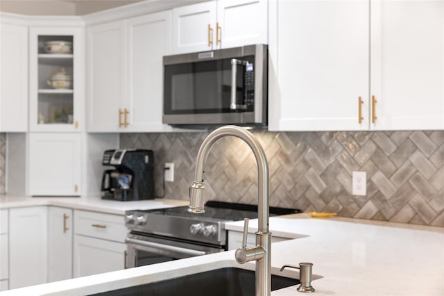 kitchen with tasteful backsplash, sink, and white cabinets