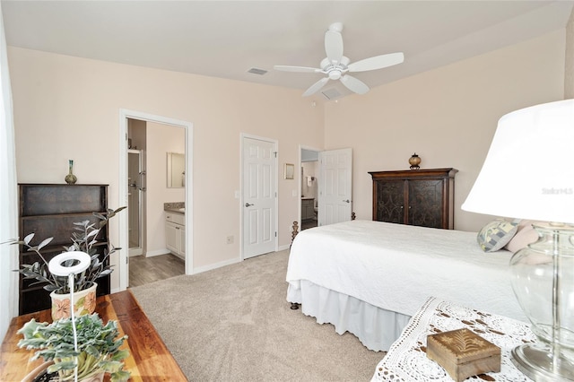 bedroom with ensuite bathroom, ceiling fan, and light carpet