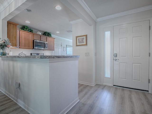 kitchen with light hardwood / wood-style flooring, a textured ceiling, and crown molding