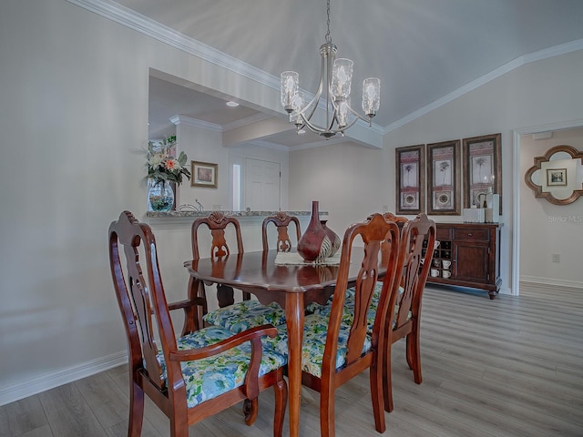 dining space featuring light hardwood / wood-style floors, a chandelier, lofted ceiling, and crown molding