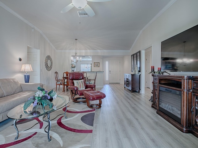 living room with light hardwood / wood-style floors, ceiling fan with notable chandelier, vaulted ceiling, and ornamental molding