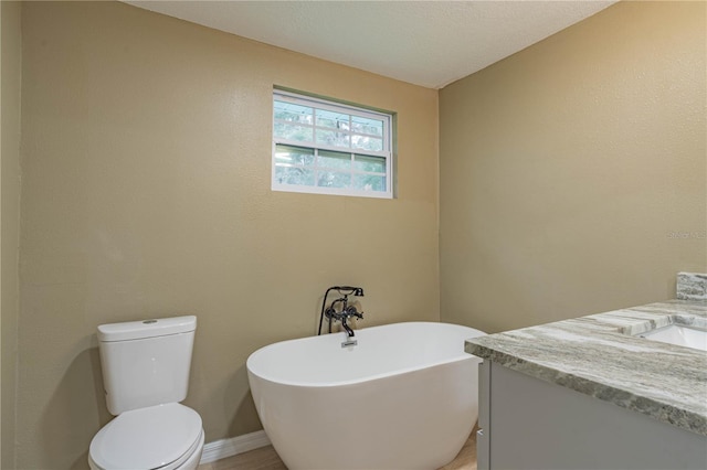 bathroom with a washtub, vanity, a textured ceiling, and toilet