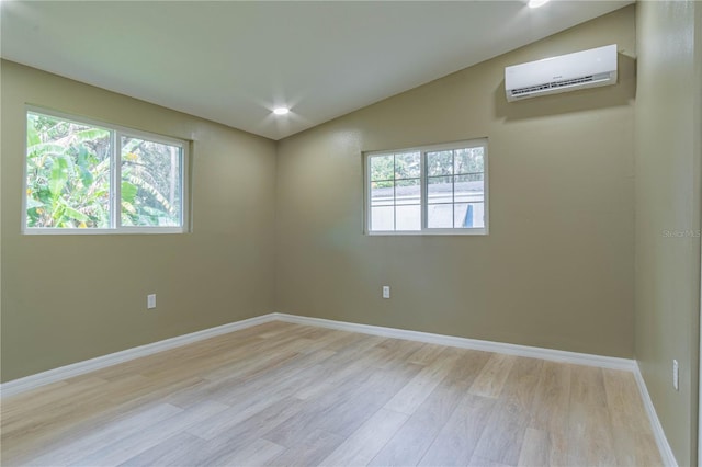 spare room with lofted ceiling, light hardwood / wood-style flooring, and a wall mounted air conditioner