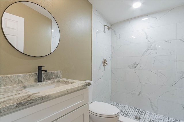 bathroom featuring vanity, toilet, and a tile shower