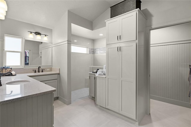 bathroom featuring a tile shower, a textured ceiling, a wealth of natural light, and vaulted ceiling