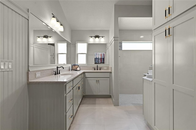 bathroom with tiled shower, vanity, a textured ceiling, and tile patterned floors