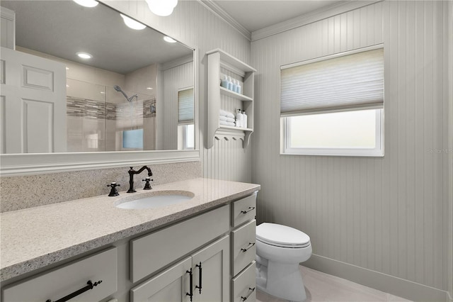 bathroom with a tile shower, toilet, wooden walls, vanity, and ornamental molding