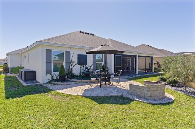 rear view of property with a sunroom, a patio area, a lawn, and roof with shingles