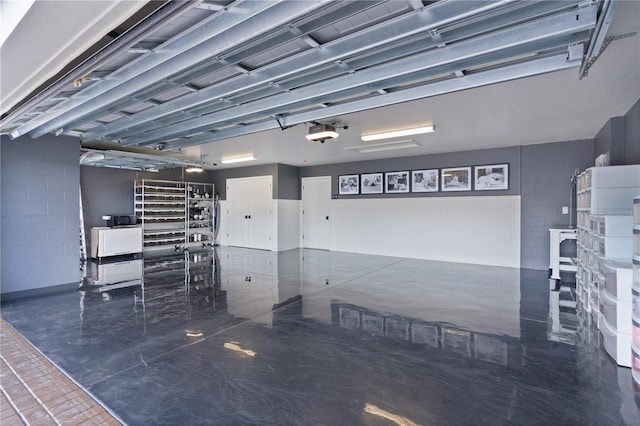 garage featuring a garage door opener and concrete block wall