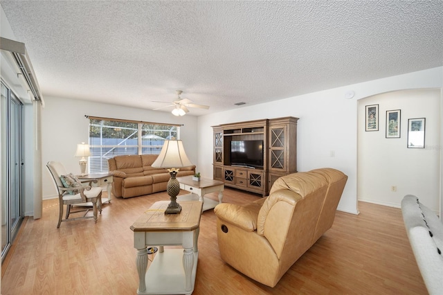 living room with ceiling fan, light hardwood / wood-style floors, and a textured ceiling