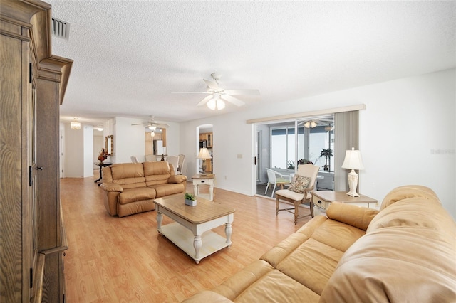 living room featuring a textured ceiling, light wood-type flooring, and ceiling fan