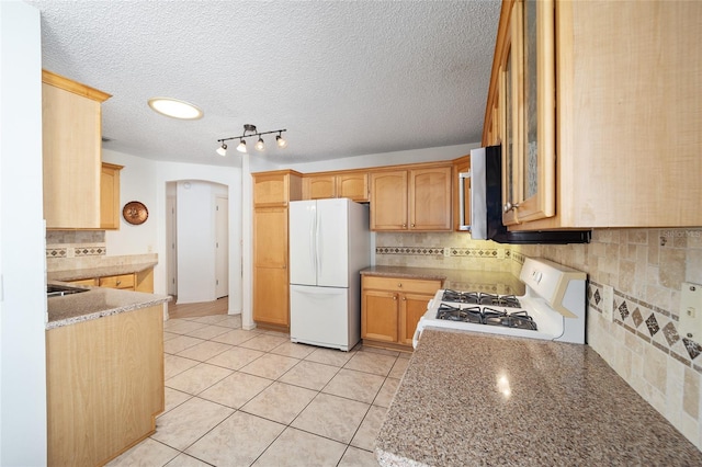 kitchen featuring white appliances, decorative backsplash, light tile patterned floors, light brown cabinetry, and light stone counters