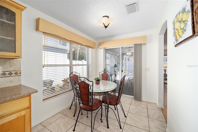 tiled dining room featuring a textured ceiling and ceiling fan