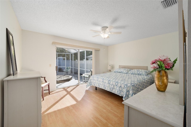 bedroom with hardwood / wood-style floors, ceiling fan, a textured ceiling, and access to outside