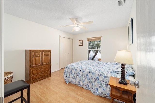 bedroom featuring a closet, ceiling fan, light hardwood / wood-style flooring, and a textured ceiling